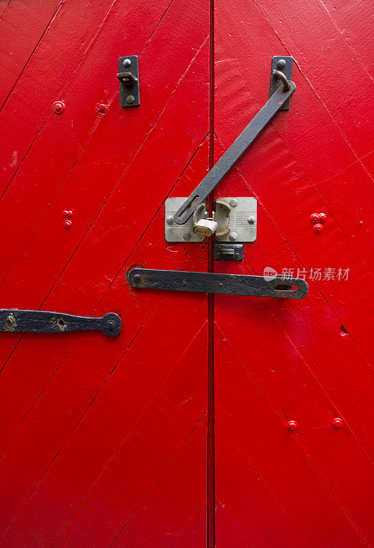 明亮的红色谷仓门与锻铁铰链