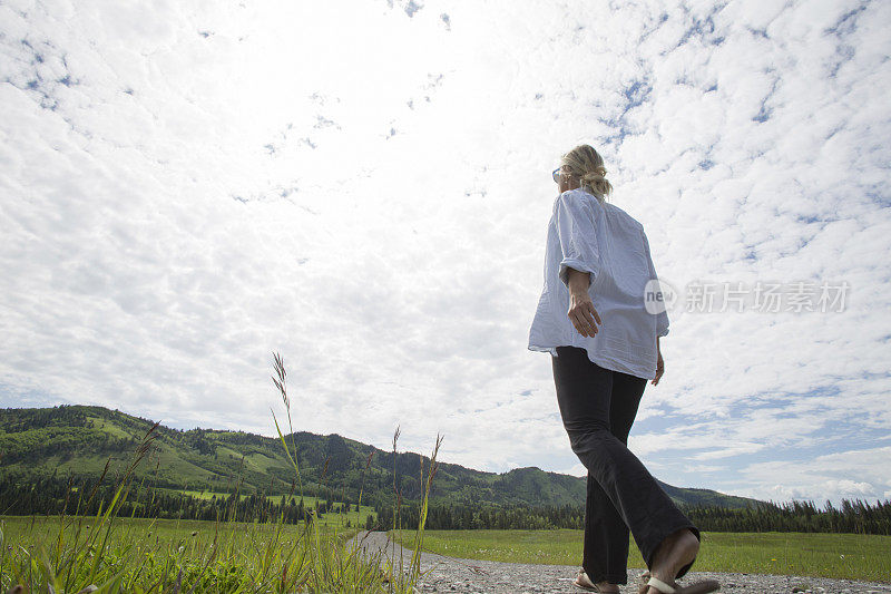 女人沿着乡间小路走向山丘