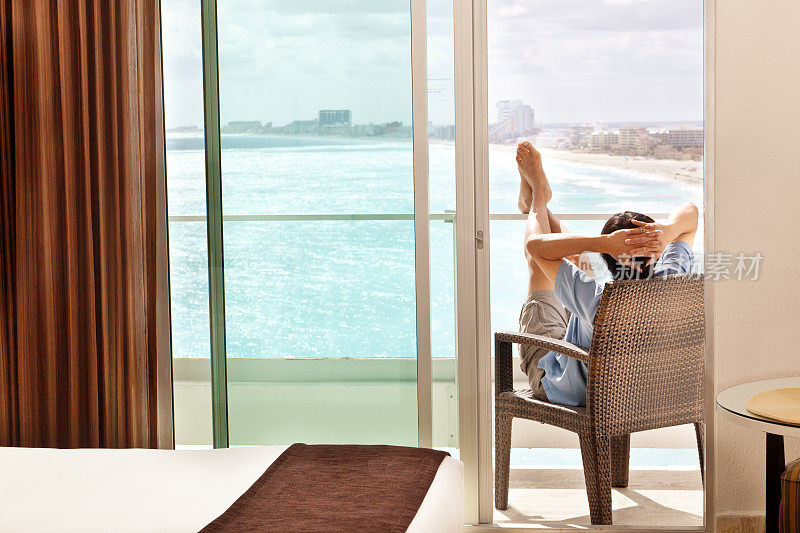 男子放松，享受酒店阳台海景海滩度假