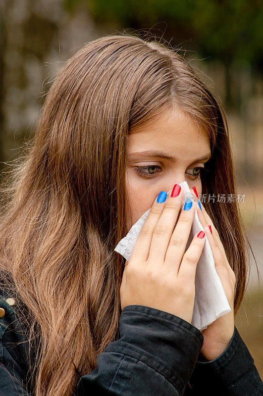 少女在秋天过敏季节用纸巾擤鼻子