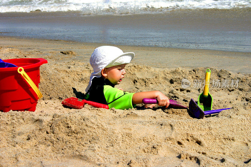 蹒跚学步的孩子在沙滩上玩沙子