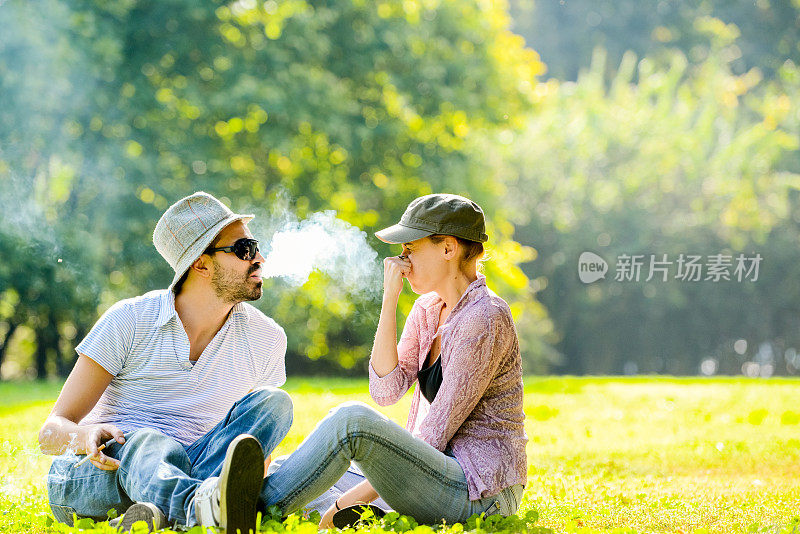 一个男人在公园抽烟，他的女朋友不喜欢
