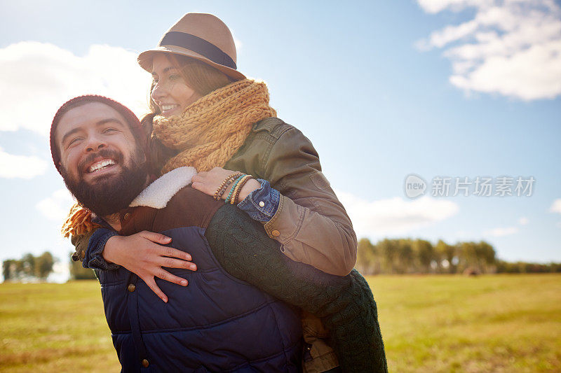 一个欢天喜地的大胡子男人背着他的女朋友在乡下