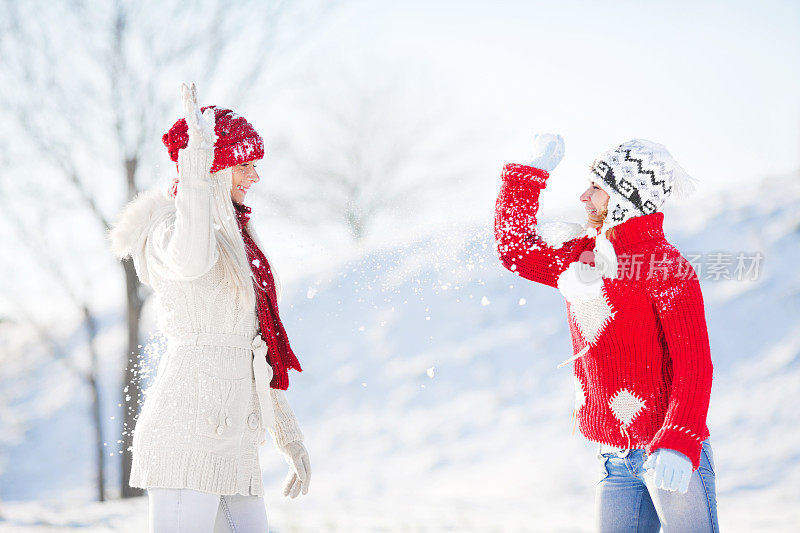 两个微笑的女人在雪地里享受。