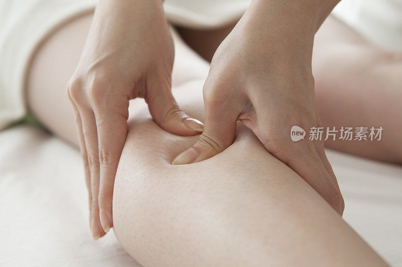 特写按摩治疗师按摩美丽的女性腿