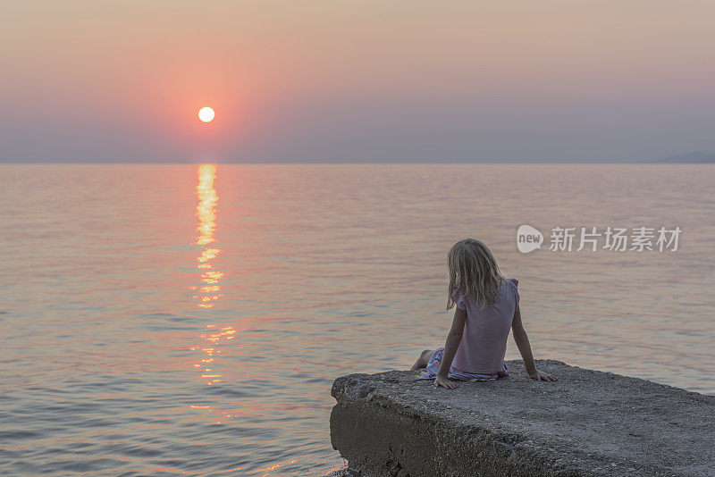 夕阳西下，年轻的女孩凝望着大海