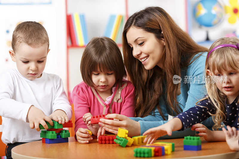 幼儿园老师和学龄前儿童在玩积木