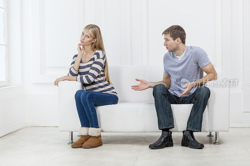 年轻的白人夫妇坐在沙发上，家庭问题