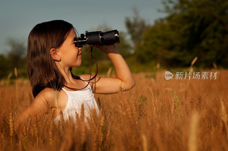 可爱的小女孩用双筒望远镜在棕茎谷地