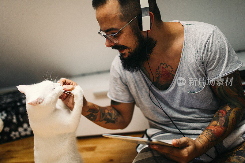 男人抱着猫，听着音乐。