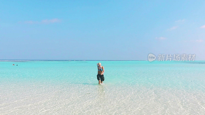 全身湿透的女人走过马尔代夫的浅水