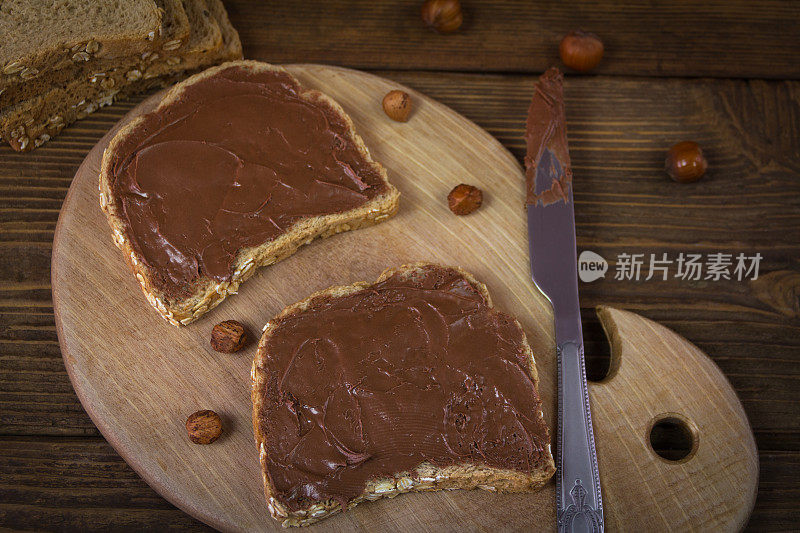 面包，巧克力奶油和榛子在木板上