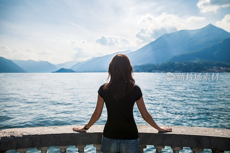 年轻女子放松在湖上的露台，意大利的后视图