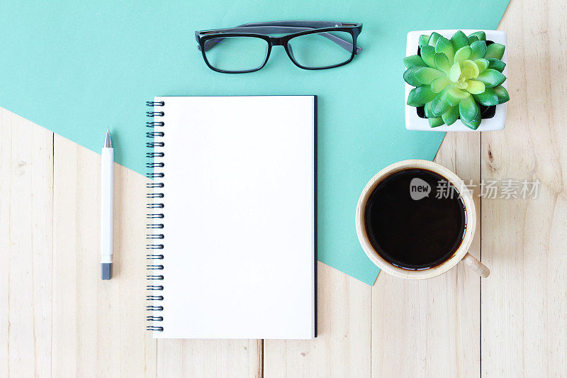 俯视图图像打开笔记本与空白页和咖啡杯在木制的背景，准备添加或模拟