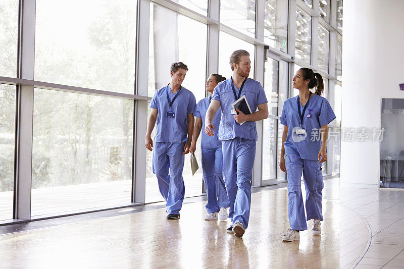 四名医护人员穿着手术服走在走廊上