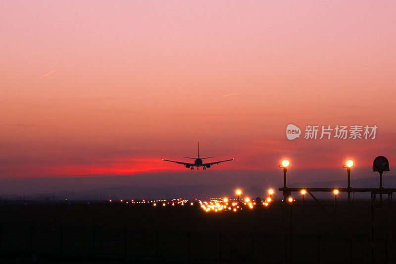 飞机在红云的背景下降落在一个机场