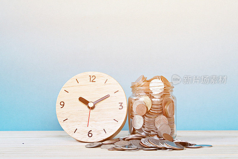 木制闹钟和白色背景上的硬币