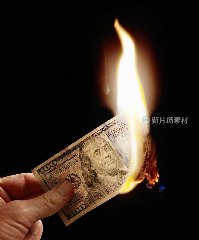 女性手里拿着正在燃烧的百元美钞