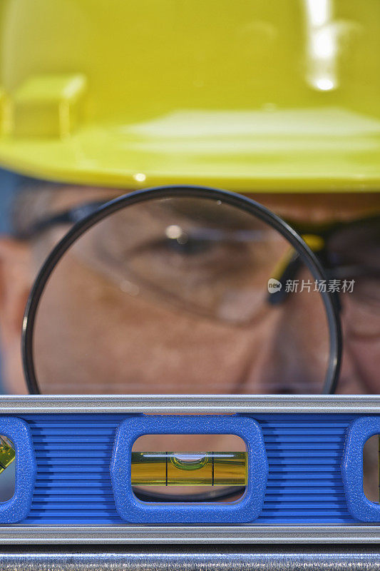 建筑工人用放大镜检查东西是否水平。