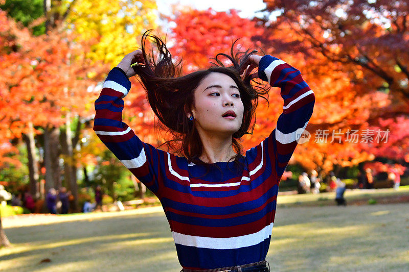 在东京的公园里，一名年轻的日本女子摆弄着她的长发