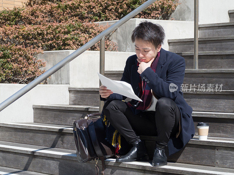 一个亚洲商人正坐在楼梯上