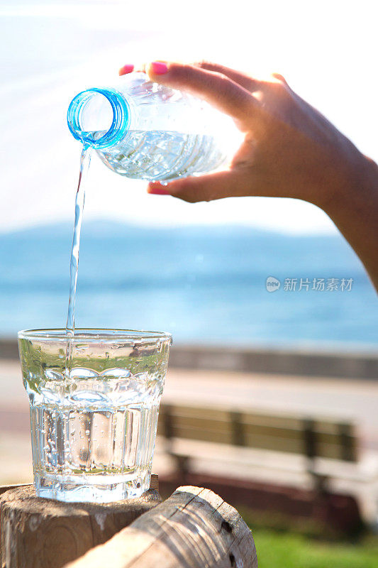 那只手正在把瓶子里的水倒在海滩上。