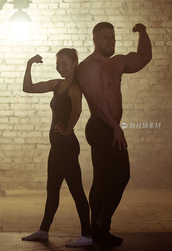 欢快的运动员夫妇展示他们强壮的手臂肌肉