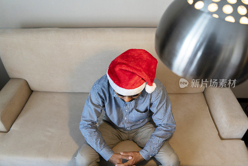 戴着圣诞帽的男人，坐在沙发上