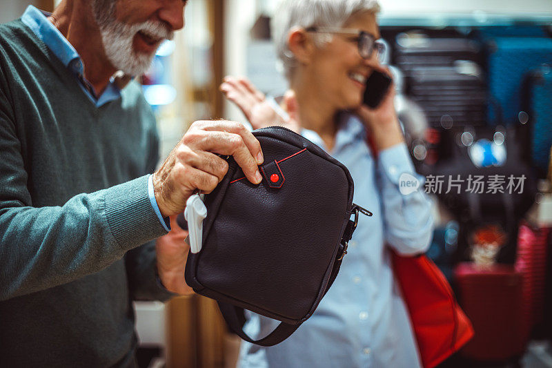 老年男子购物袋，而他的伴侣正在讲智能手机