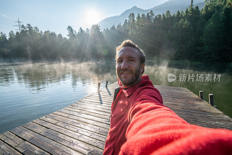 在清晨的雾中，年轻男子在湖码头上的自拍，瑞士