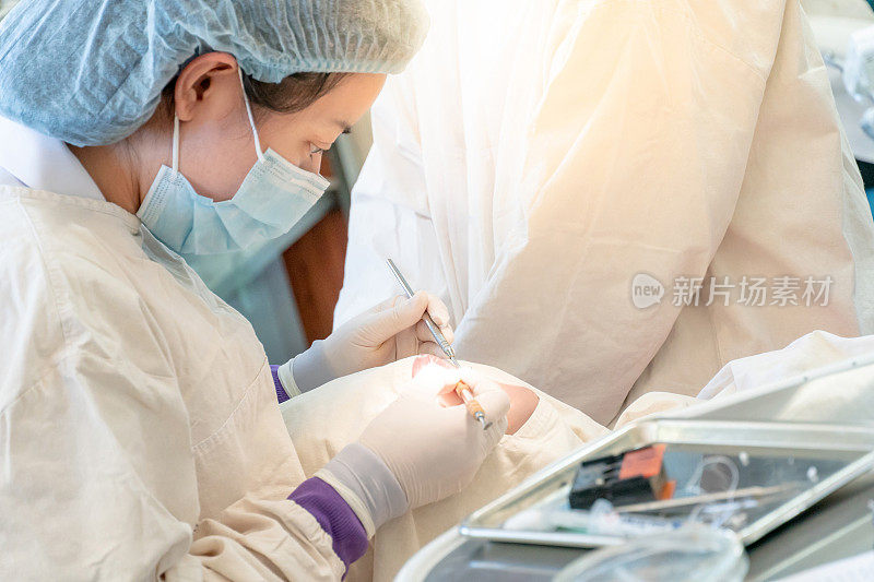 在牙科诊所使用牙科器械检查和治疗病人牙齿的女性亚洲牙医。牙科程序和医疗。