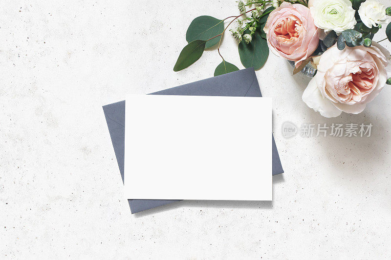 女性婚礼，生日模拟场景。空白纸贺卡，信封。一束桉树叶，粉红的英国玫瑰和毛茛花。具体表的背景。平躺,