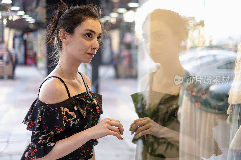 年轻的女士望着商店的橱窗