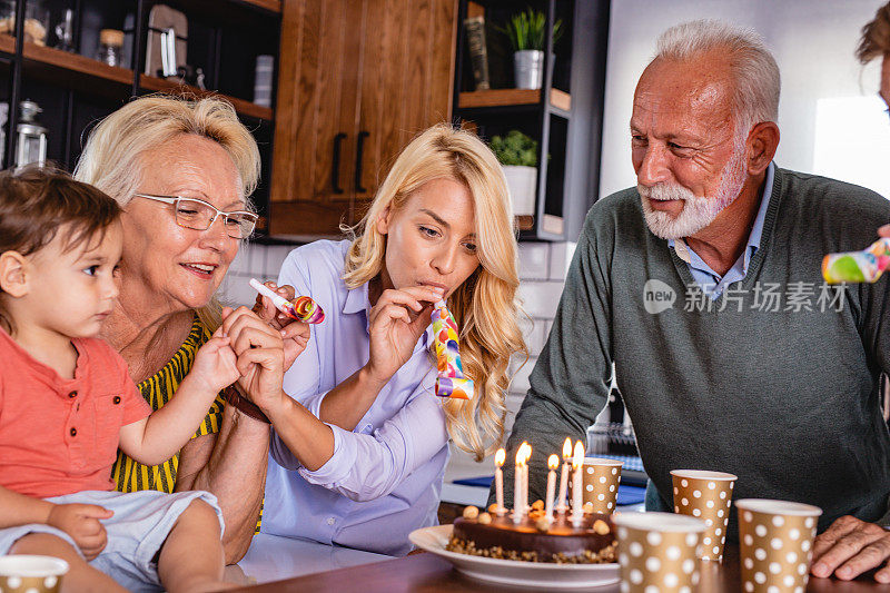 几代同堂的家庭庆祝生日，并在蛋糕上吹生日蜡烛