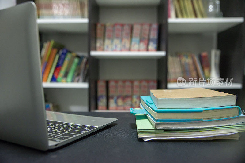 学生的课桌上放着日记和书，为了考试而学习。木制书桌，配有台式笔记本电脑，笔记本，书和日记在图书馆。书桌为学生概念。