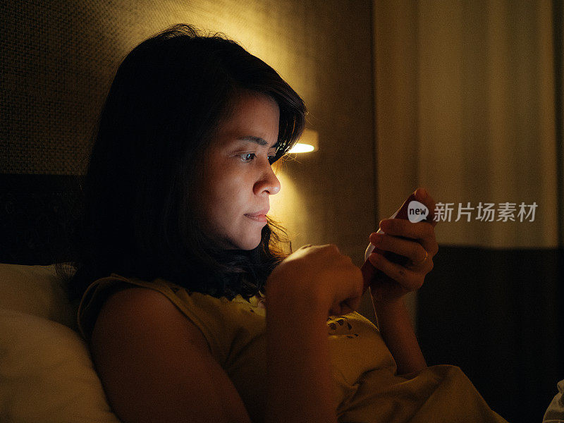 一名亚洲女性在深夜使用智能手机。