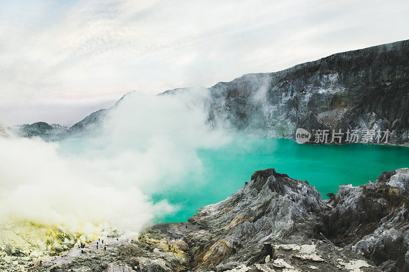 印度尼西亚东爪哇岛的伊真火山火山口的绿松石色湖泊上的日出，山脉和硫磺蒸汽