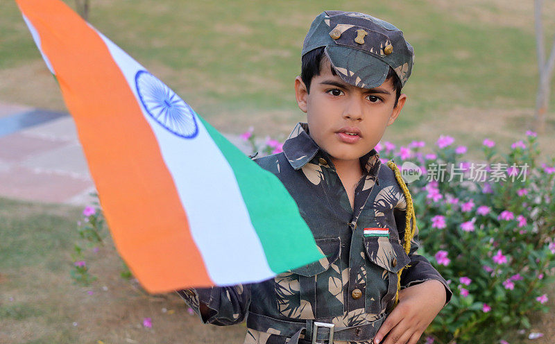 小学生手持旗帜，身穿军装，在户外拍摄独立日庆祝活动肖像。
