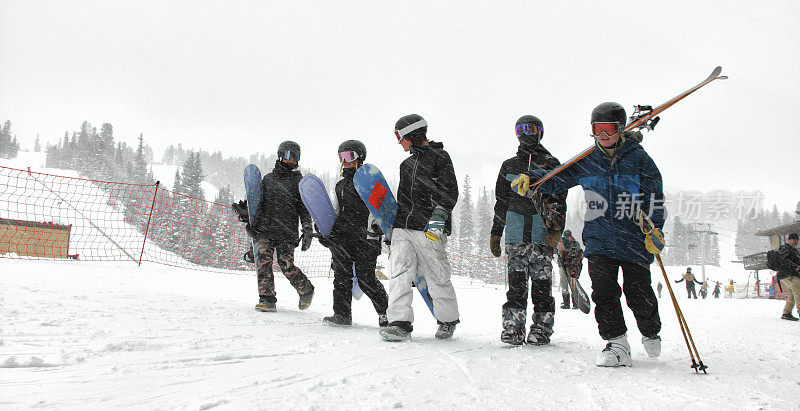 一小队滑雪者和滑雪板在完整的冬季装备一起走在Eldora滑雪度假村附近的博尔德，科罗拉多州在一个下雪的，阴天的冬天