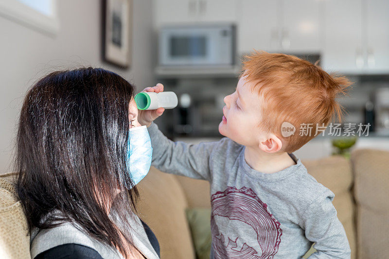 小男孩用红外温度计测量他生病的母亲的温度