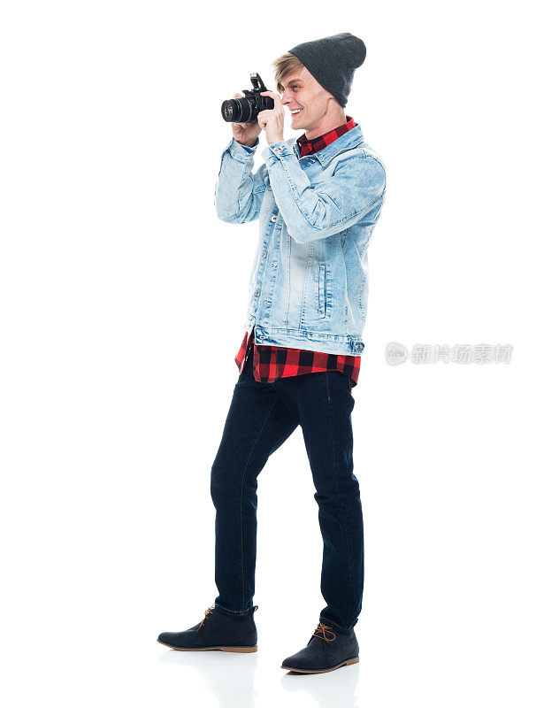 白人年轻男性摄影师穿着靴子站在白色背景前