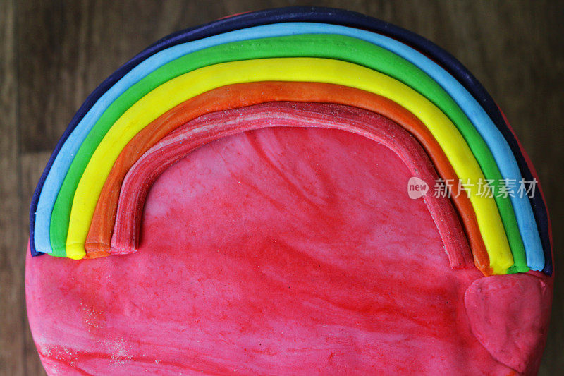 自制彩虹蛋糕的图像，巧克力海绵抹上黄油奶油糖霜，装饰着方旦糖糖霜彩虹和云彩，俯瞰