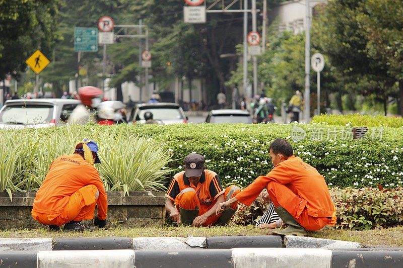 在雅加达市中心，身穿橙色衣服的人们清理路边的草地和公园