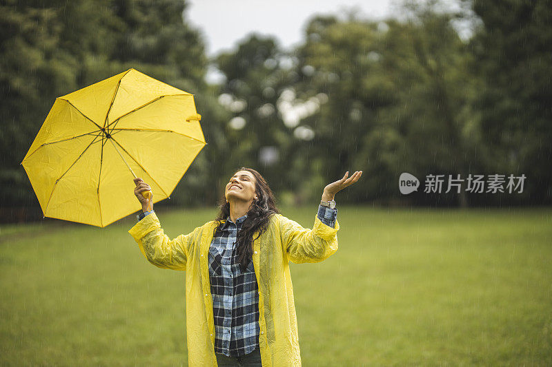 快乐的女人微笑着行走在雨天