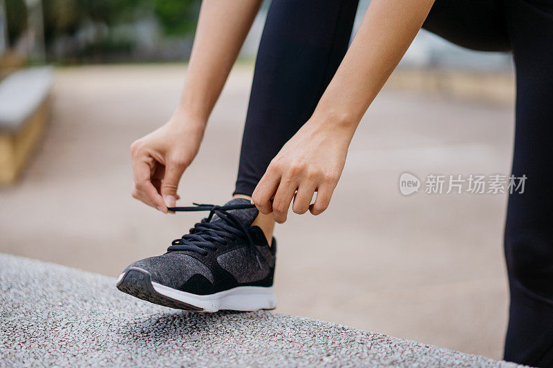 年轻的亚洲女人系鞋带，准备跑步