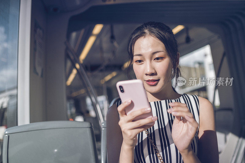 年轻女子在乘坐地铁上下班时使用手机