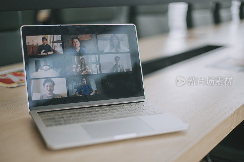 共享办公室的笔记本电脑屏幕上显示8名亚洲华人面对视频会议