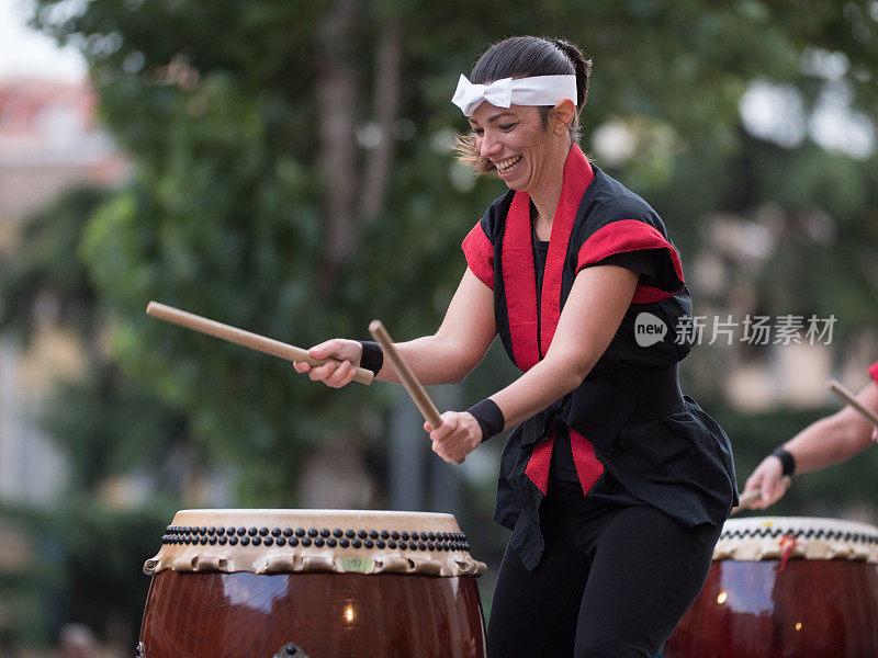 在公共户外活动中弹奏日本传统音乐鼓的女孩