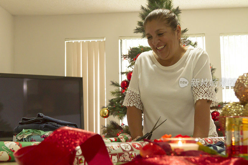 近肖像画拉丁成熟的女人切割和包装圣诞礼物在拉丁家庭在美国