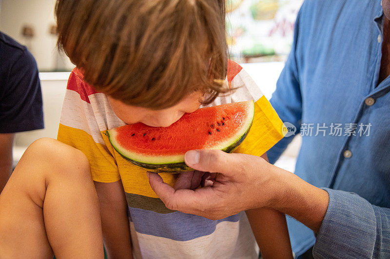 孩子和父亲在厨房里吃着新鲜的西瓜